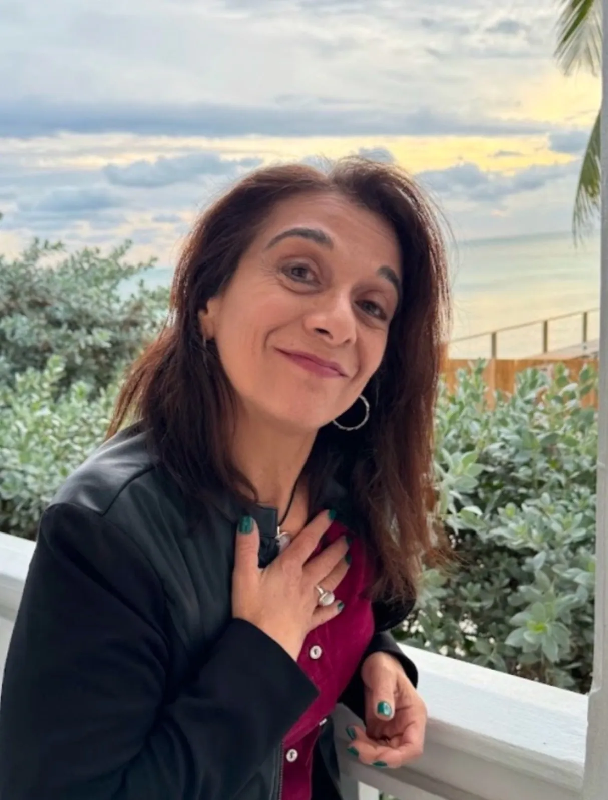 Mary L. Bondi, LMHC, CHT, smiling on a balcony overlooking the ocean in Fort Lauderdale