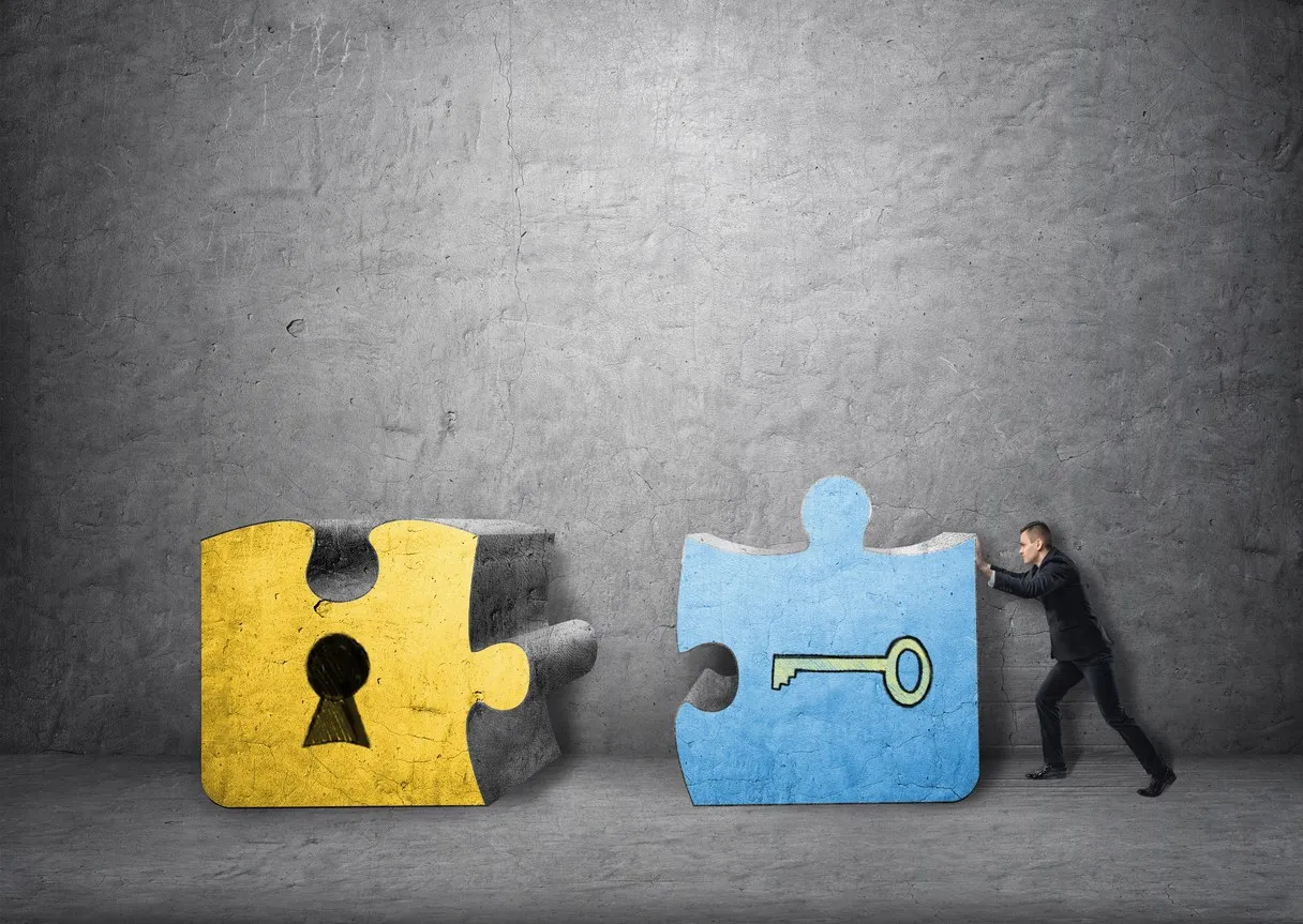 Two puzzle pieces, a lock and a key, being pushed together